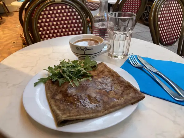 Crepe salata con rucola, una tazza di caffè e un bicchiere d'acqua, un assaggio dei piatti tipici parigini.