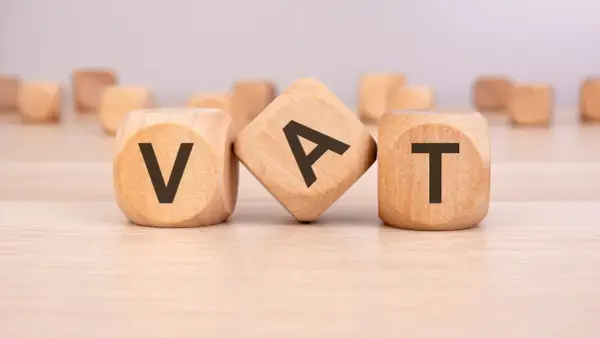 Drewniane klocki z literami V, A, T tworzą słowo VAT. To ważny element każdego formularza zaw-fa.