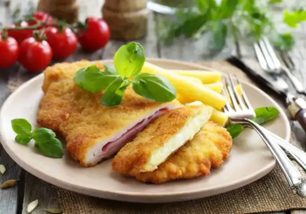 Schab po szwajcarsku z serem i szynką, panierowany, podany z makaronem i bazylią.