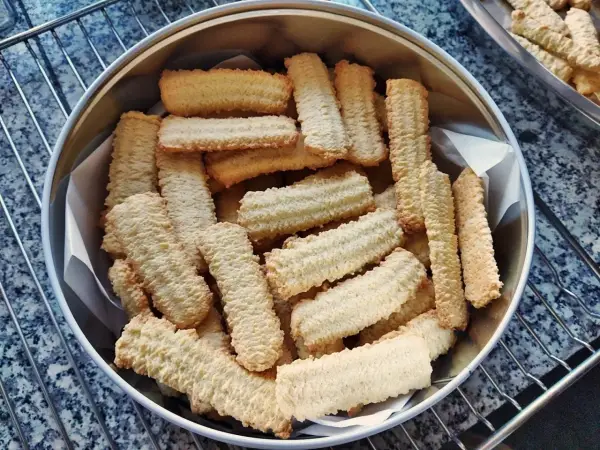 Stos pysznych, chrupiących ciastek z maszynki, ułożonych w metalowej puszce. Idealne na popołudniową herbatę.