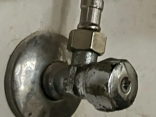 Metalowy zawór wodny, pokazujący, jak odkrecic zawor z woda. Widoczny śrubunek i pokrętło.