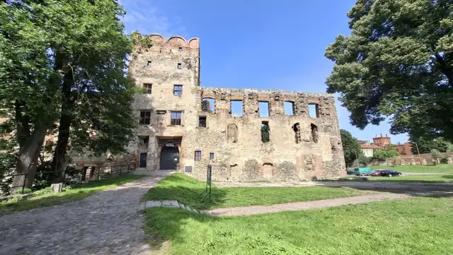 Kamienne mury i wieża zamku w Ząbkowicach Śląskich, otoczone zielenią, zapraszają do odkrywania historii.