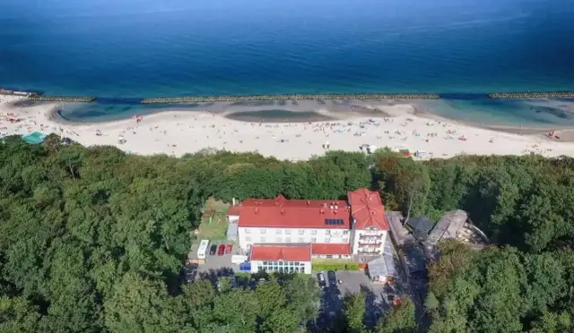 Widok z lotu ptaka na resort spa plaza otoczony lasem, z plażą i morzem w tle.