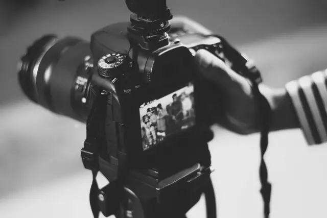 Dłoń trzyma aparat, gotowa do uchwycenia chwili. Może to być moment z życia gwiazdy, który trafi na okładkę, albo praca paparazzi w akcji.