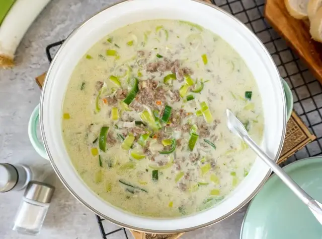 Cremige Lauchsuppe mit Hackfleisch in einem Topf, garniert mit Lauchringen.