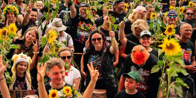 Uśmiechnięci ludzie z słonecznikami na jednym z 3 festiwali muzycznych w Polsce. Radość i pokój na twarzach.