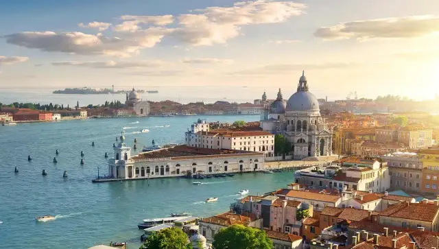 Venice cityscape with canals, boats, and historic buildings under a sunny sky.
