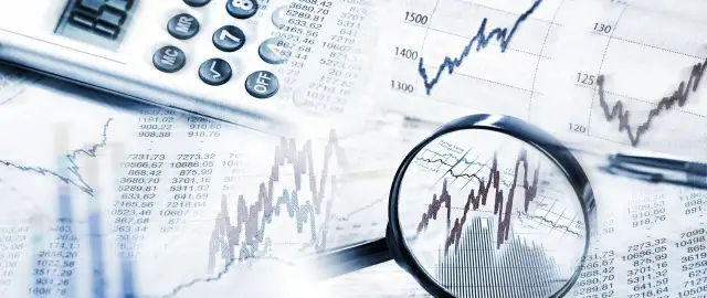 Analiza wykresów i tabel finansowych, kalkulator i lupa wskazują na analizę obligacji korporacyjnych emisji.