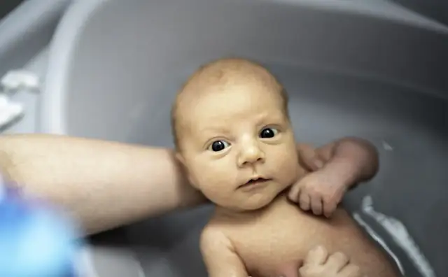 Niemowlę w wanience, z zaciekawieniem patrzy na świat. Czy można kąpać dziecko po szczepieniu? Tak, jeśli nie ma przeciwwskazań lekarza.