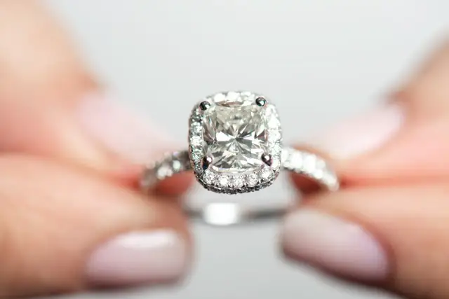 Ein funkelnder Verlobungsring mit einem großen Diamanten im Zentrum, umgeben von kleineren Steinen. Die Reinheit der Diamanten ist beeindruckend, fast wie eine Tabelle der Perfektion.
