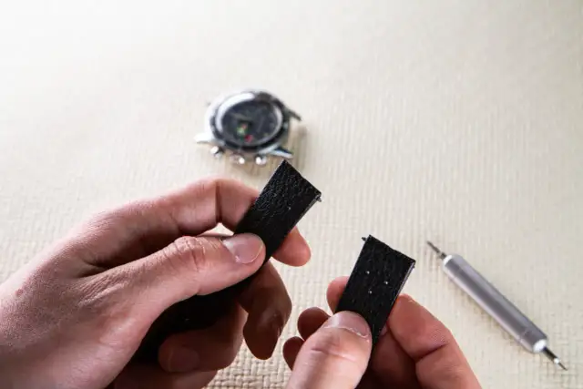 Maintenant, découvrez comment changer un bracelet de montre connectée. Un outil est visible à côté du bracelet noir démonté.