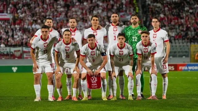 Reprezentacja Polski zawodnicy w białych strojach, gotowi do gry. Na murawie widać dumę i determinację.