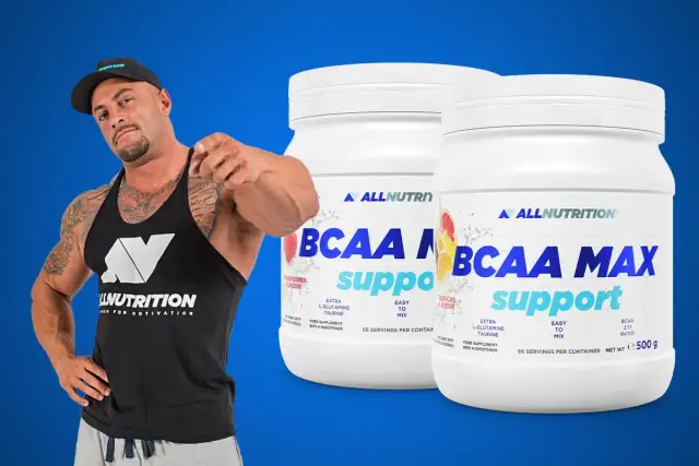 Muskularny mężczyzna w czapce i koszulce Allnutrition wskazuje palcem na dwa słoiki suplementu BCAA MAX.