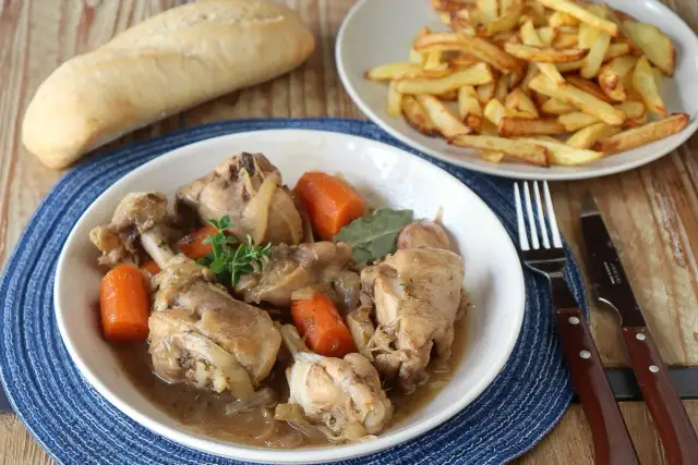 Guiso de pollo con patatas de la abuela, tierno y jugoso, acompañado de patatas fritas crujientes y pan.