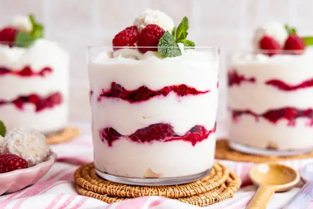 Raffaello-Dessert im Glas mit Himbeeren und Kokosflocken, garniert mit Minze.