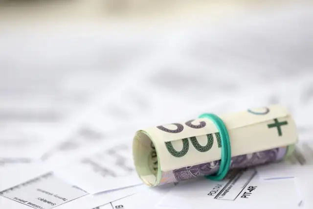 Zrolowane banknoty na dokumentach podatkowych. Przygotowanie do rozliczenia ulgi rehabilitacyjnej 2026.