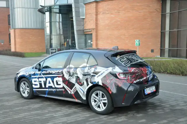 Samochód hybrydowy z grafiką STAG, informującą o paliwie: cng i hybryda. Nowoczesny design podkreśla ekologiczny napęd.