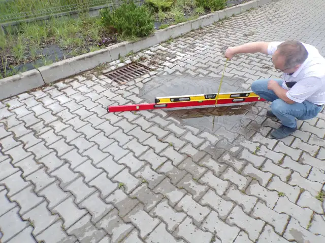 Mężczyzna sprawdza poziom wody na chodniku z kostki brukowej.