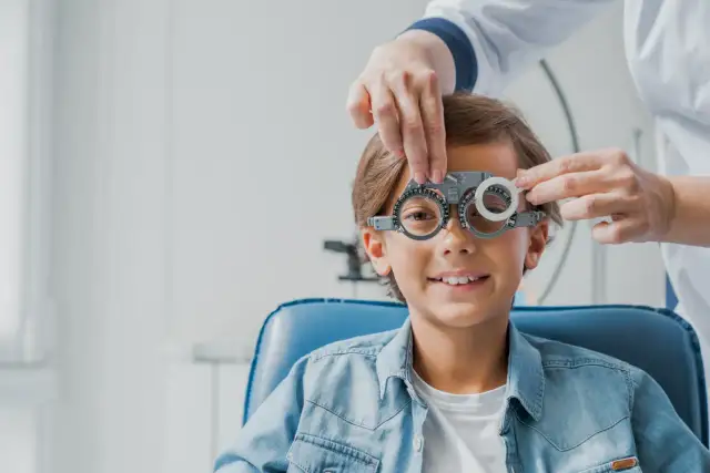 Chłopiec w okularach próbnych podczas badania wzroku u optometrysty.