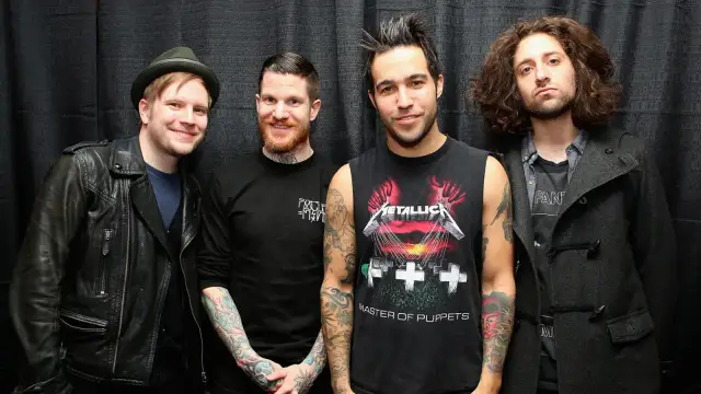 Czterech mężczyzn z zespołu Fall Out Boy pozuje do zdjęcia na tle czarnej kurtyny.
