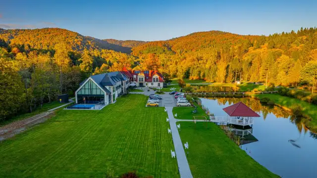 Hotel SPA w Bieszczadach otoczony jesiennym lasem, z basenem i stawem.