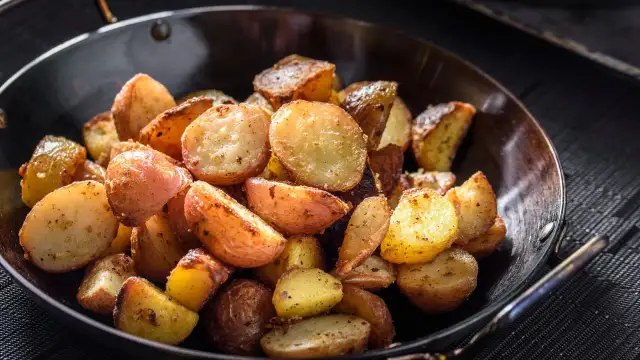 Goldbraune bratkartoffeln mit Ei, knusprig gebraten und würzig gewürzt, serviert in einer Pfanne.