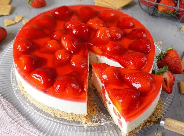Ein köstlicher Erdbeerkuchen ohne Backen, mit frischen Erdbeeren und rotem Tortenguss auf cremigem Boden.