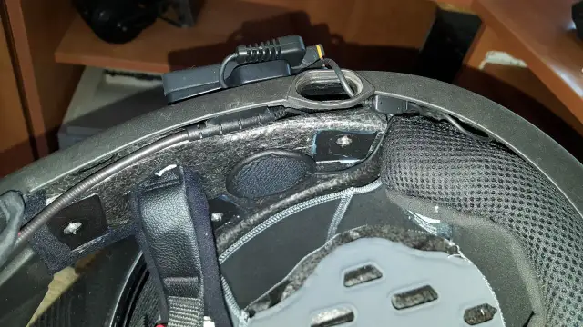 Montaż interkomu w kasku motocyklowym. Widoczne przewody i moduł komunikacyjny zamocowane wewnątrz skorupy.