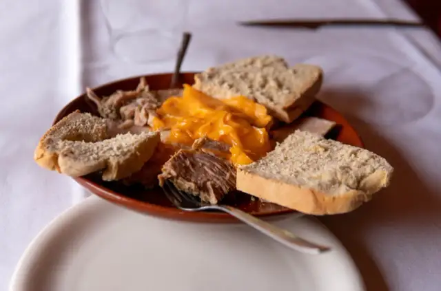 Plato de lomo en manteca con pan rústico y una salsa cremosa de queso.