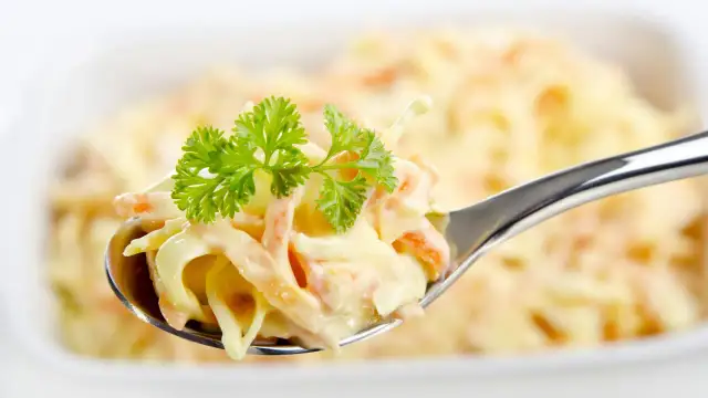 Ein Löffel cremiger Coleslaw Salat, garniert mit Petersilie. Perfekt für ein einfaches coleslaw salat rezept.