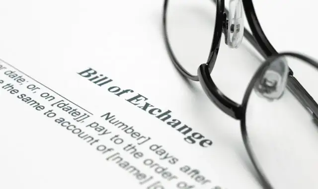 Okulary leżą na dokumencie "Bill of Exchange". To jest weksel, czyli papier wartościowy, który zobowiązuje do zapłaty określonej sumy pieniędzy.