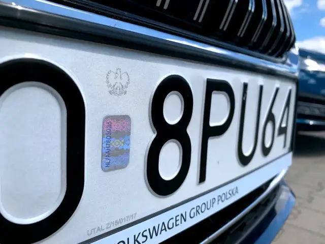 Zbliżenie na polską tablicę rejestracyjną z numerem 8PU64 i hologramem.