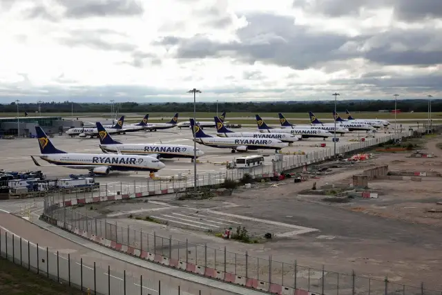 Wiele samolotów Ryanair na płycie lotniska. To typowy widok dla lotnisk w Anglii, gdzie tanie linie lotnicze obsługują duży ruch pasażerski.