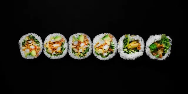 Sześć kawałków futomaki, czyli dużych rolek sushi, z awokado, warzywami i smażonymi kawałkami.
