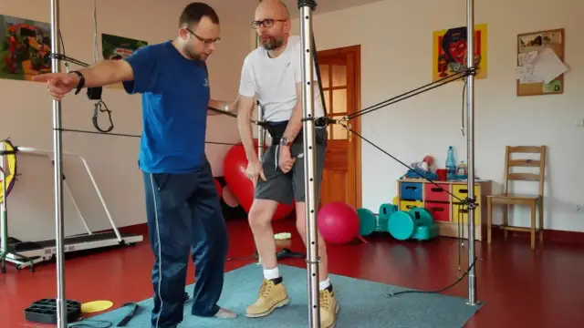 Fizjoterapeuta pomaga pacjentowi ćwiczyć z użyciem sprzętu do rehabilitacji po udarze mózgu.