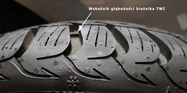 Zbliżenie na bieżnik opony z widocznym wskaźnikiem głębokości TWI.