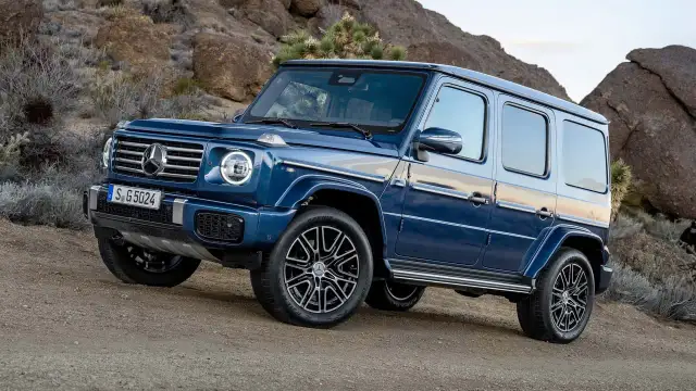Niebieski G-wagon na pustynnym, skalistym podłożu.