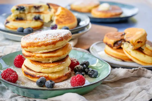 Fluffige Buttermilch Pancakes, bestäubt mit Puderzucker und garniert mit frischen Beeren. Ein Genuss für jeden Morgen!