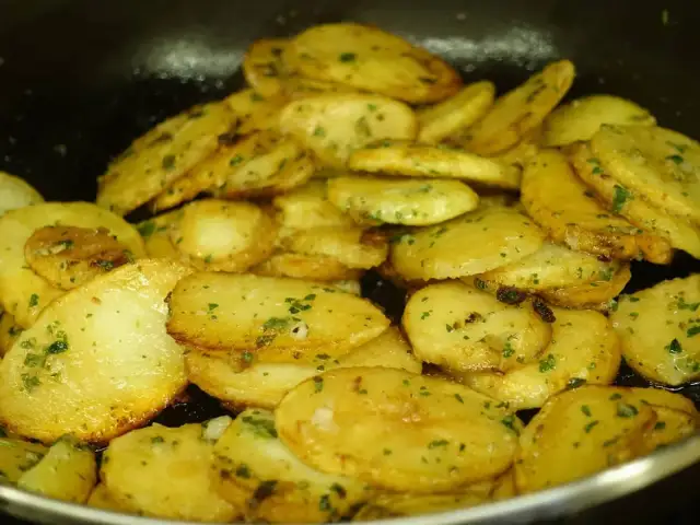 Patatas panaderas al horno crujientes, doradas y con perejil picado, listas para disfrutar.