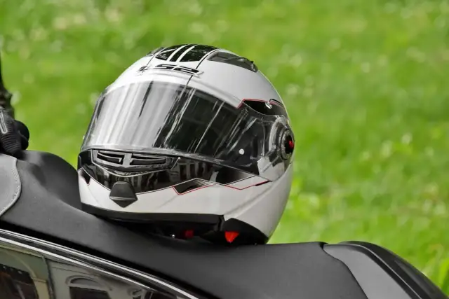 Biały kask motocyklowy z czarnymi i czerwonymi akcentami, gotowy do naprawy.