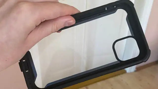 Dłoń trzyma czarne etui na telefon z przezroczystym tyłem. Dowiedz się, jak wyczyścić etui na telefon, aby wyglądało jak nowe.