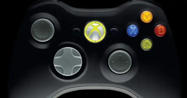 Zbliżenie na czarny kontroler Xbox 360 z podświetlonym logo Xbox i kolorowymi przyciskami.