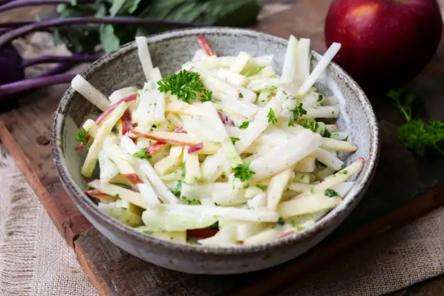 Kohlrabi Salat mit Apfelstücken und frischer Petersilie in einer rustikalen Schüssel.
