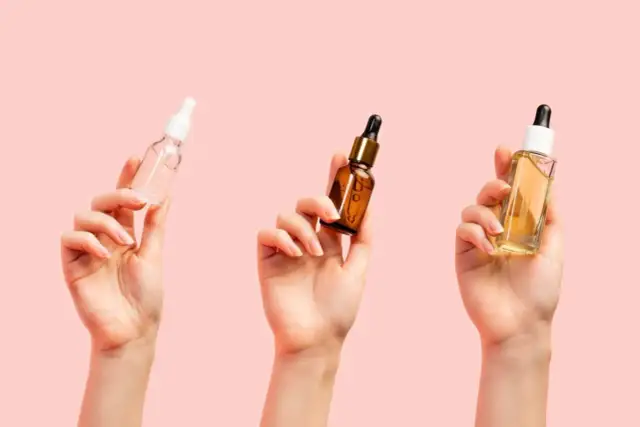 Trzy dłonie trzymają buteleczki z serum. Zastanawiasz się, jakie serum do twarzy po 40. wybrać?
