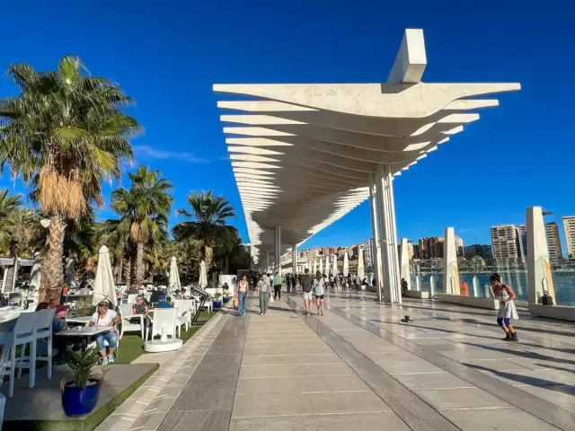 Spacerem po Muelle Uno w Maladze, gdzie zobaczyć można nowoczesną architekturę i palmy.
