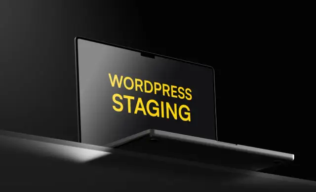 Laptop z napisem "WORDPRESS STAGING" na ekranie, w ciemnym otoczeniu.