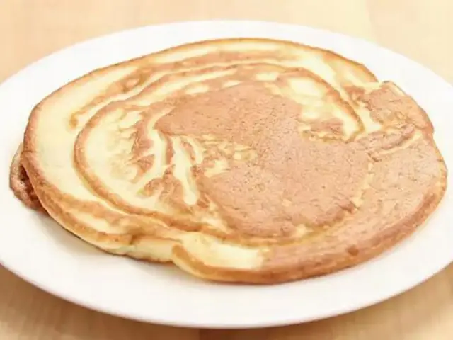 Ein goldbrauner Pfannkuchen ohne Ei auf einem weißen Teller, perfekt für ein leichtes Frühstück.