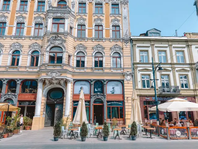 Elegancka kamienica z ogródkiem piwnym i stolikami na chodniku w Łodzi.