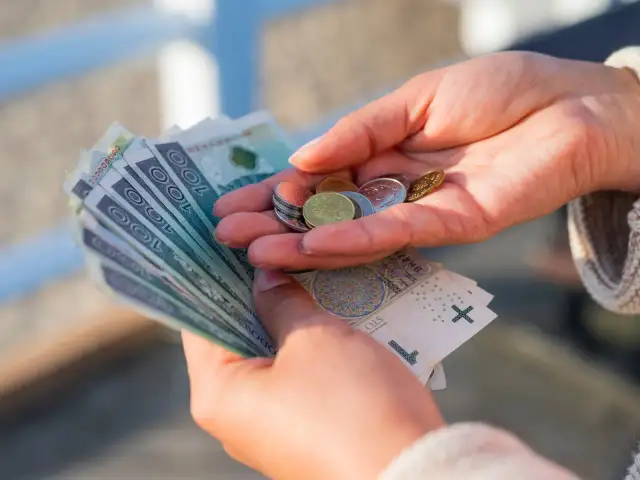 Dłonie liczą pieniądze, symbolizując oszczędności na przyszłość, być może związane z wiekiem emerytalnym kobiet.