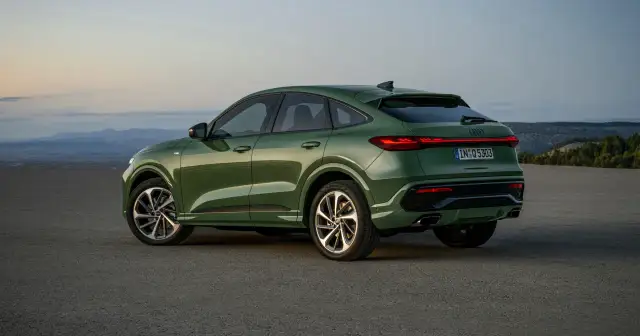 Zielony q5 audi z elegancką linią dachu, zaparkowany na pustkowiu o zachodzie słońca.